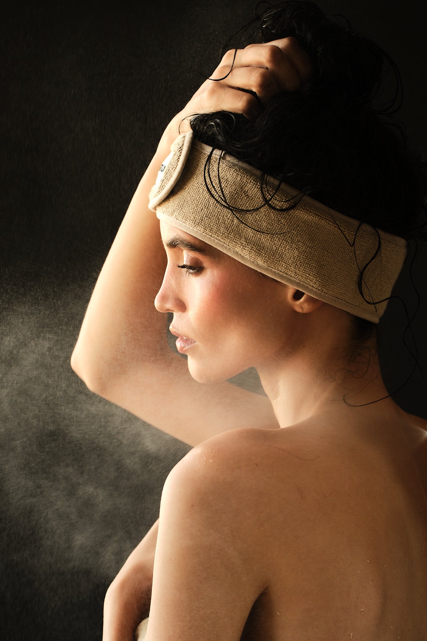 Woman with a towel on her head against a dark background